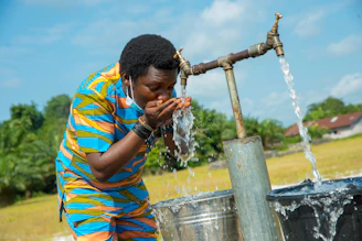 man in yellow blue and red stripe polo shirt holding water hose