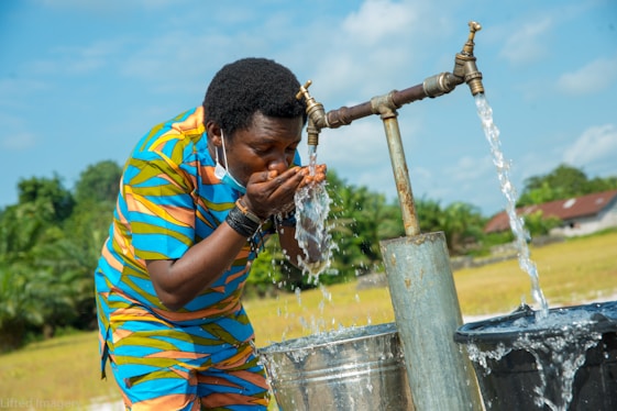 man in yellow blue and red stripe polo shirt holding water hose