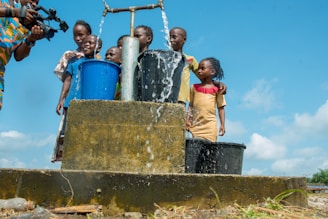 2 boys standing on blue plastic bucket