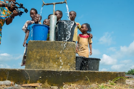 2 boys standing on blue plastic bucket