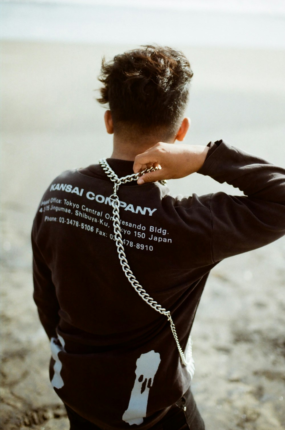 man in black long sleeve shirt wearing silver chain necklace