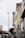 A street view featuring a vintage vertical sign that reads 'Johnson Storage Moving' on the side of a building. The surrounding area includes various storefronts, parked cars along the sidewalk, and a speed limit sign indicating 30 mph. A painted teddy bear mural can be seen near the top of one building, and the sky is overcast, adding a muted tone to the scene.
