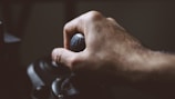 A close-up of a hand pulling a slot machine lever.