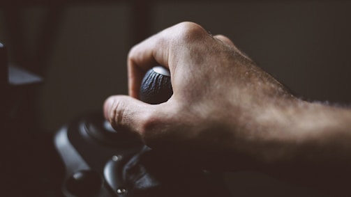 A close-up of a hand pulling a slot machine lever.