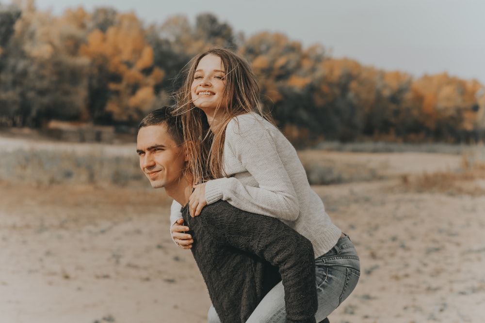 woman in white sweater and black pants sitting on brown sand during daytime