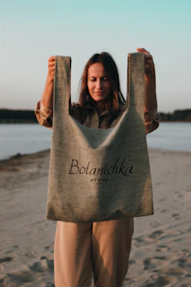 A happy shopper holding a tote bag filled with beach gear, walking along a sandy shore.