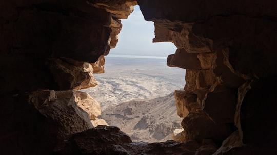 brown rock formation near body of water during daytime in Masada Israel