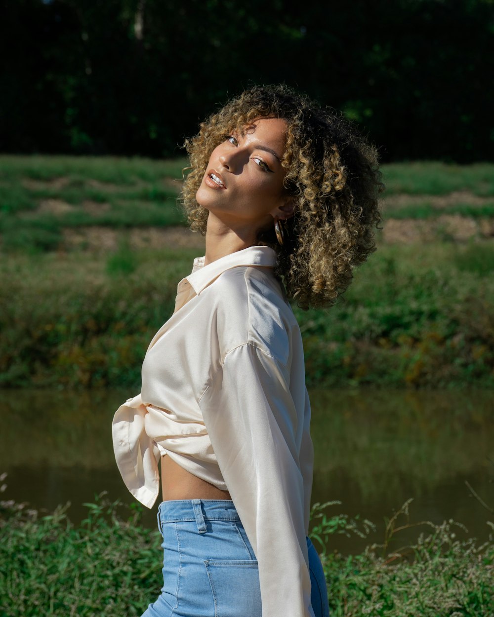 woman in white long sleeve shirt and blue denim jeans standing near green grass field during