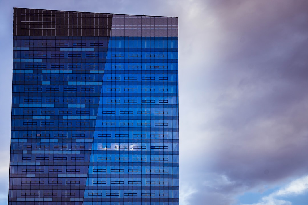 blue glass walled high rise building under white clouds