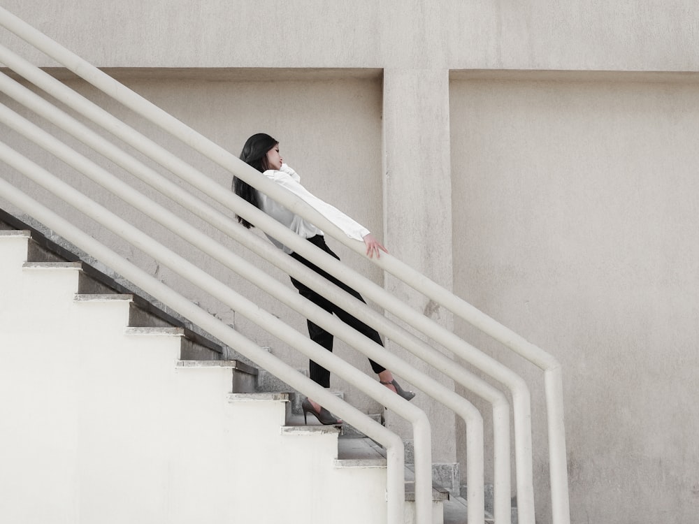 woman in black shirt and black pants sitting on white staircase