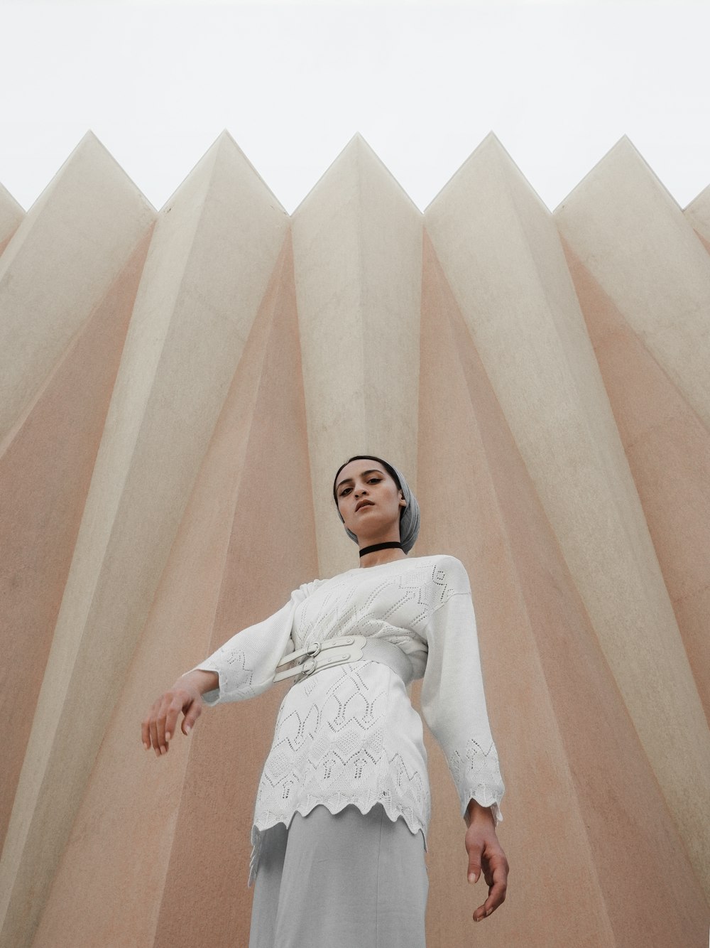 woman in white long sleeve shirt standing beside white concrete wall