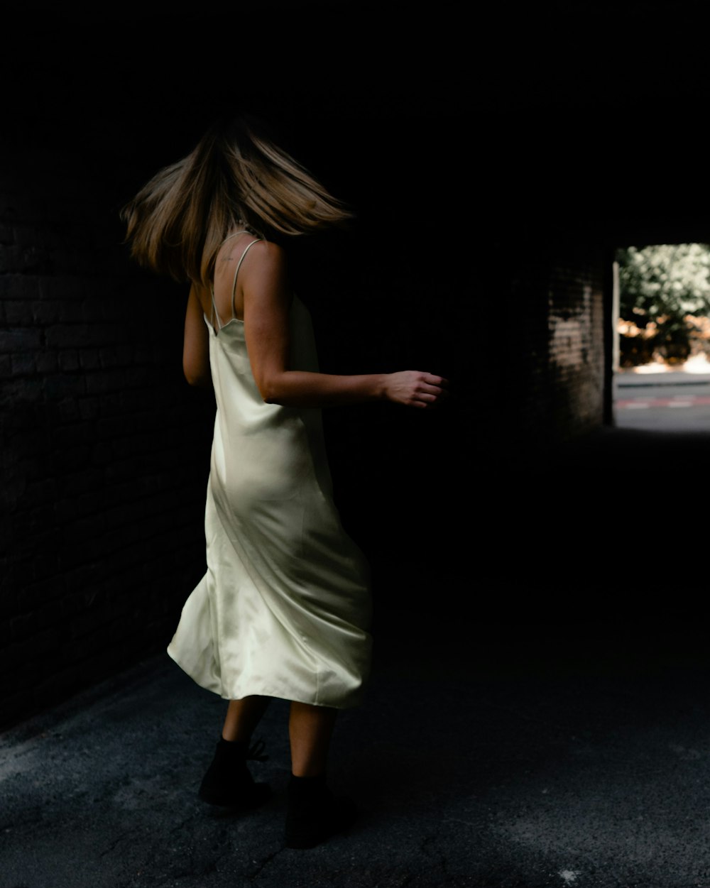 woman in white sleeveless dress standing on black asphalt road during night time