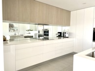After photo of the same kitchen featuring sleek white cabinets, modern fixtures, and quartz countertops.