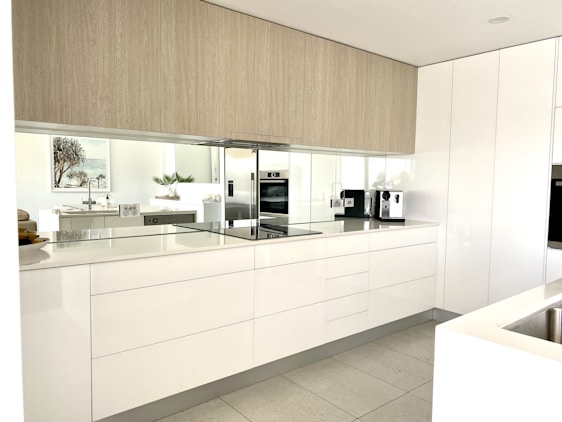 A bright, modern kitchen corner featuring sleek beige and gray cabinetry with minimalist decor.