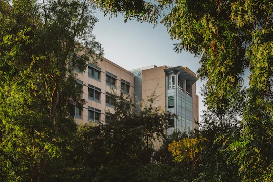 A modern eco-friendly building surrounded by green trees under a clear sky.
