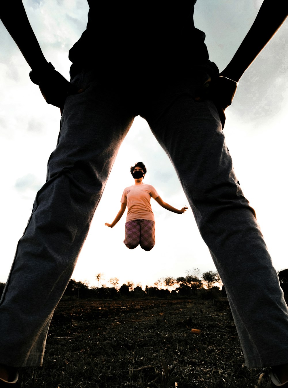 man in white t-shirt and black pants jumping on brown ground during daytime