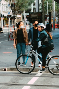 man and woman riding on bicycle on sidewalk during daytime