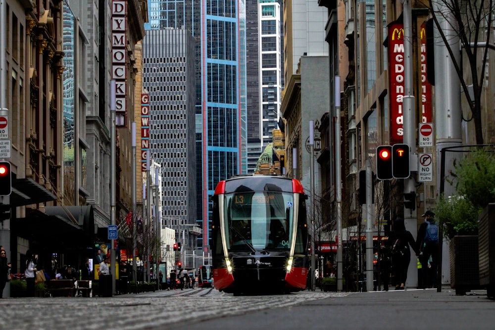black and red tram on road between high rise buildings during daytime