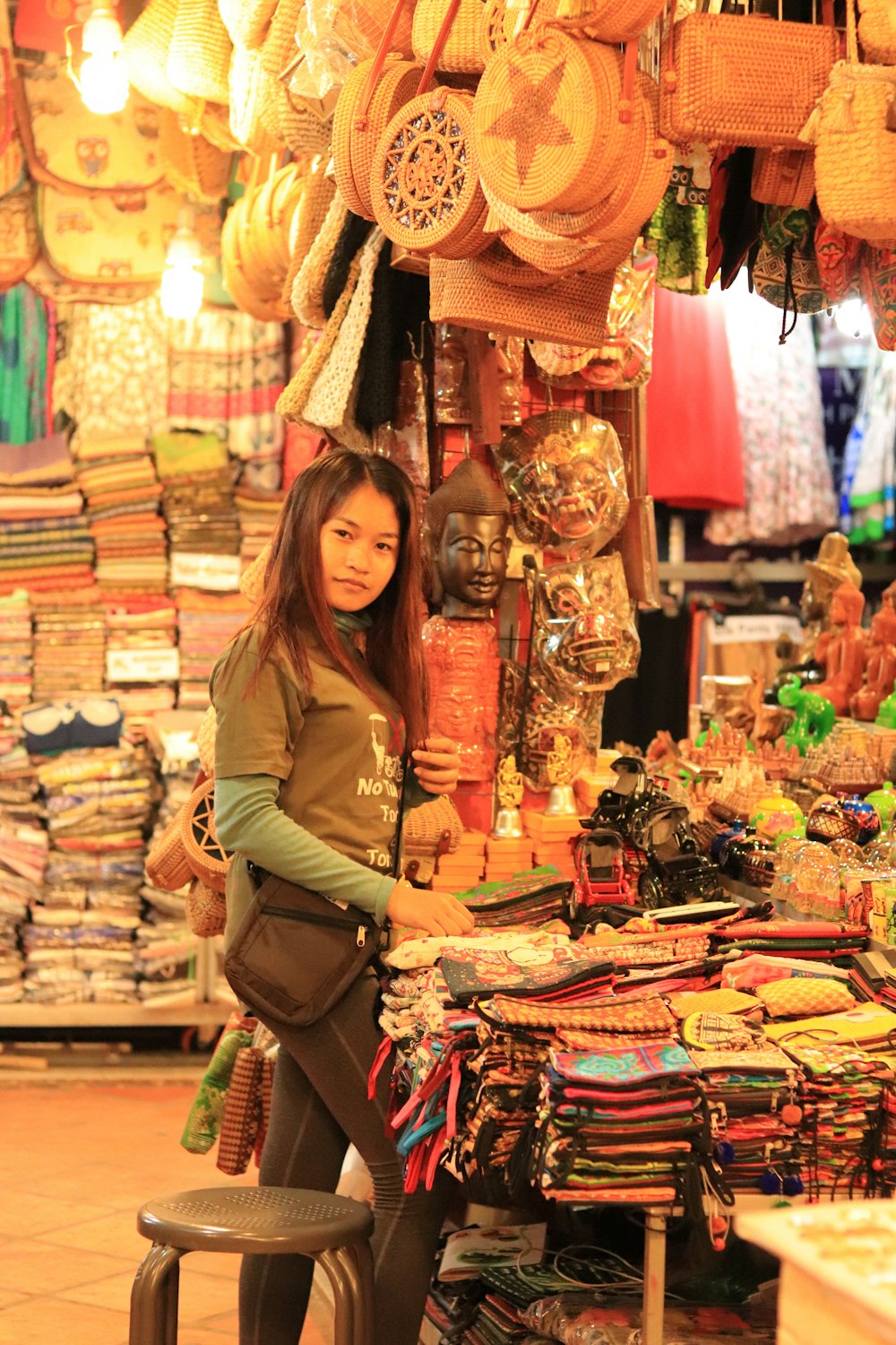 Donna in camicia marrone a maniche lunghe in piedi accanto a pacchetti di plastica assortiti