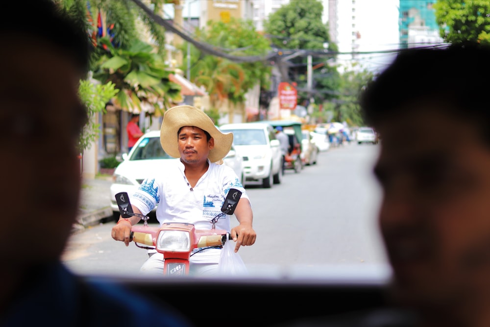 man in white shirt and brown hat sitting on motorcycle during daytime