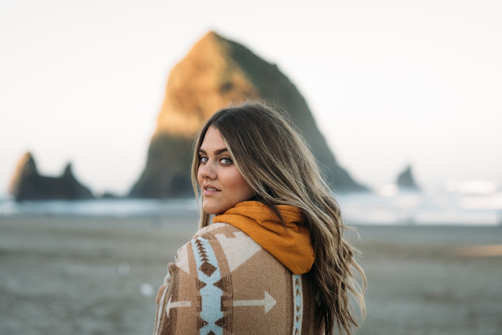 woman in brown and black hoodie standing near body of water during daytime