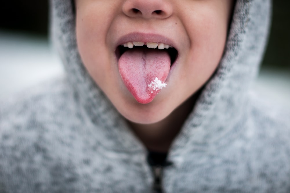 Persona con sudadera con capucha gris mostrando lengua