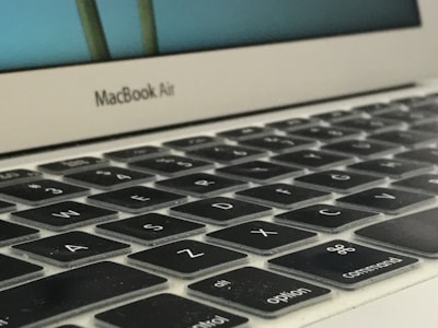 Close-up of hands typing on a MacBook keyboard with repair tools nearby.