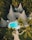 A resort-style setting with several cone-shaped thatched-roof huts surrounded by lush tropical vegetation. A vibrant blue swimming pool is centrally located on a wooden deck, with pathways winding through neatly manicured gardens.