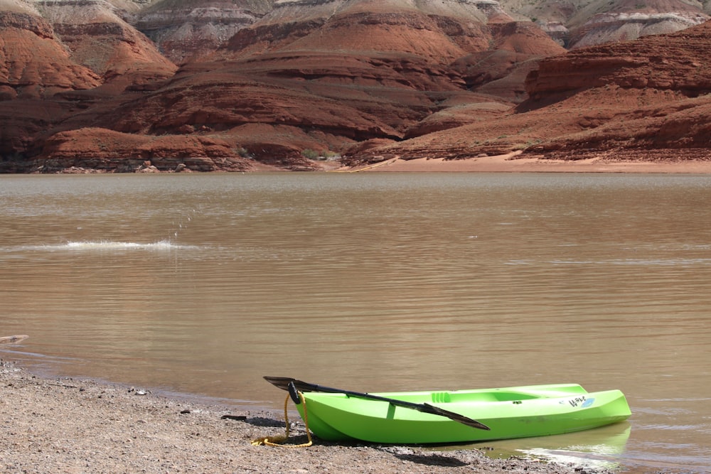 green kayak on brown sand near body of water during daytime