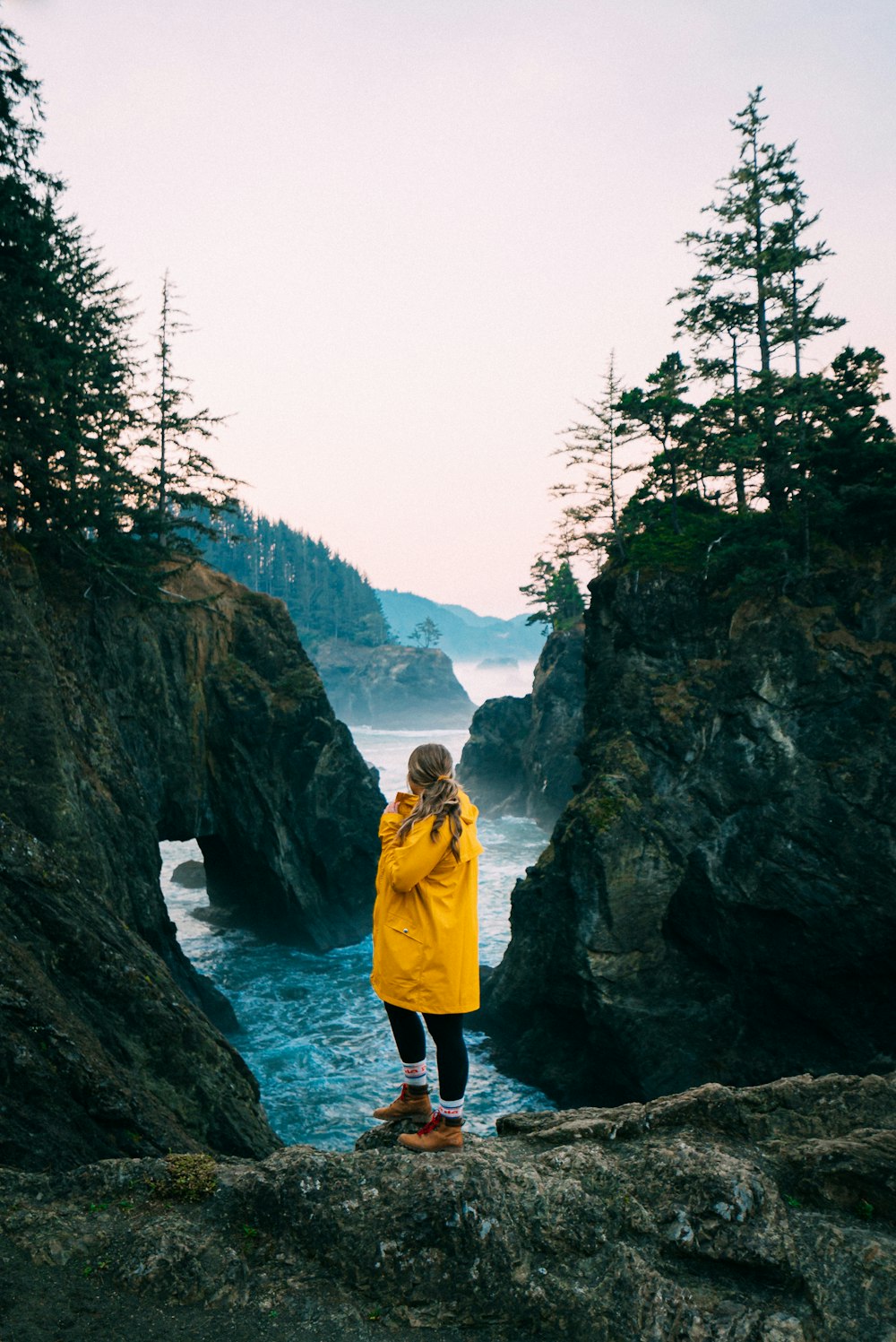 2 women standing on rock formation near body of water during daytime