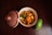 A bowl containing a spicy mango salad with diced mangoes and green peppers, garnished with mustard seeds. Next to it is a fresh green mango on a dark wooden surface.