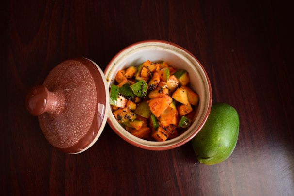 A vibrant bowl of mango pickle with visible chunks of raw mango and spices.