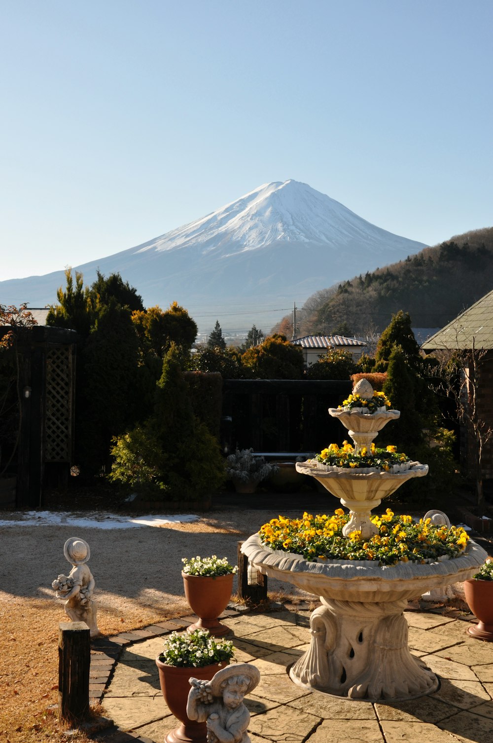 white and brown concrete fountain near green trees and mountain under blue sky during daytime