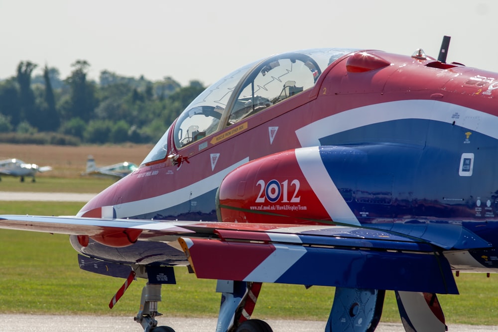 blue and red jet plane on green grass field during daytime