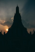 A serene sky with soft clouds parting to reveal a radiant temple silhouette.