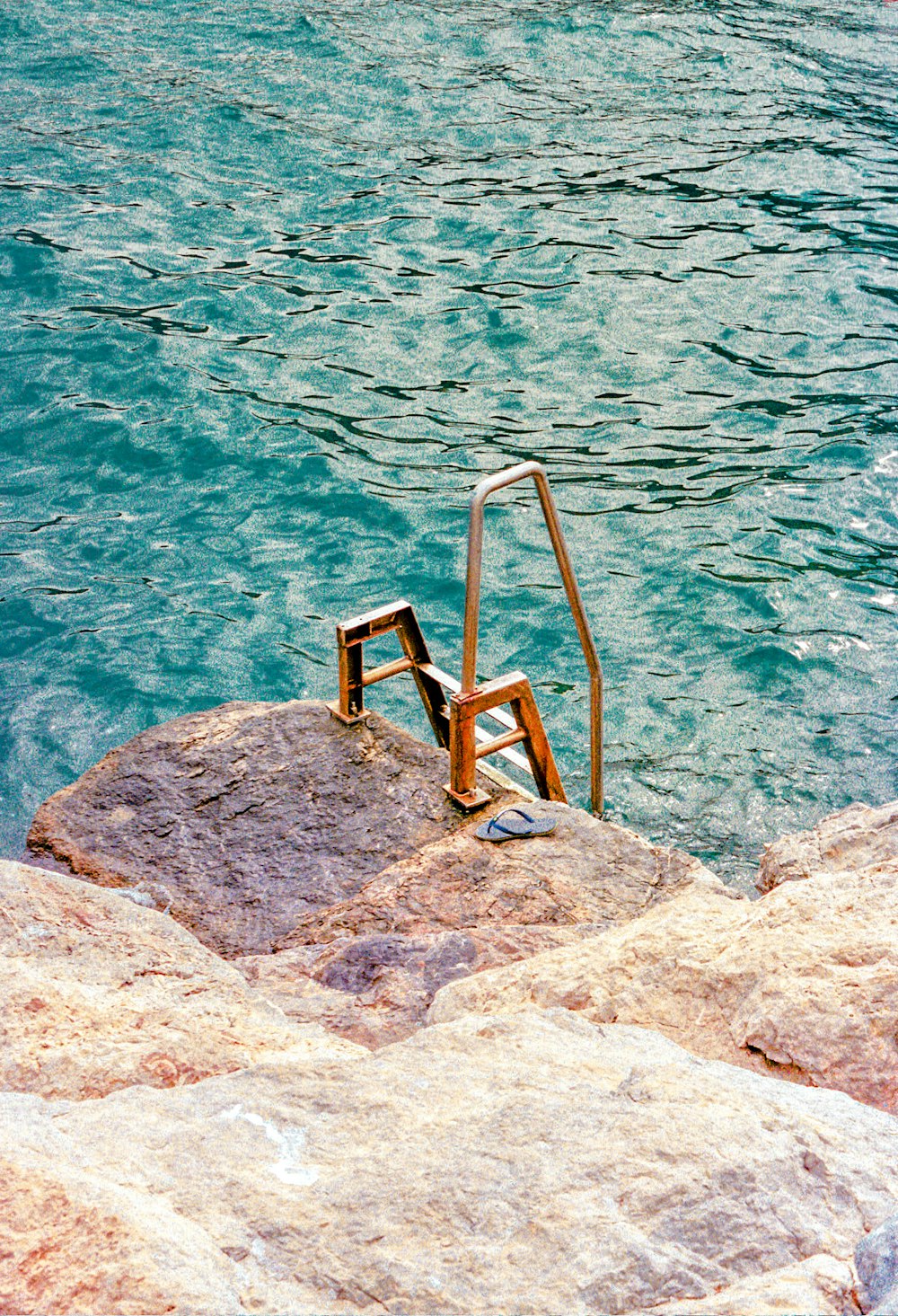 Escalera de madera marrón en roca gris cerca del cuerpo de agua durante el día