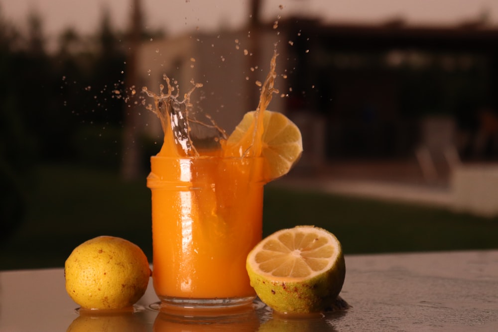 orange juice in clear drinking glass with sliced lemon