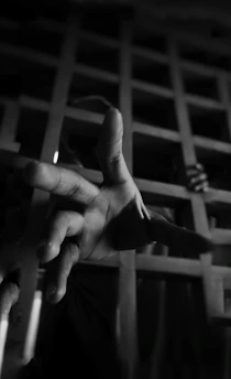 A close-up of a weathered hand holding a worn letter, symbolizing hope and connection from inside prison walls.