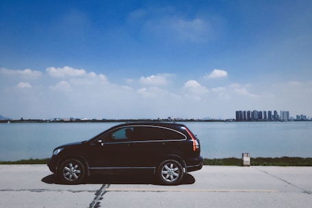 A sleek black Cadillac Escalade parked outside Oyster Bay Airport under a clear blue sky.