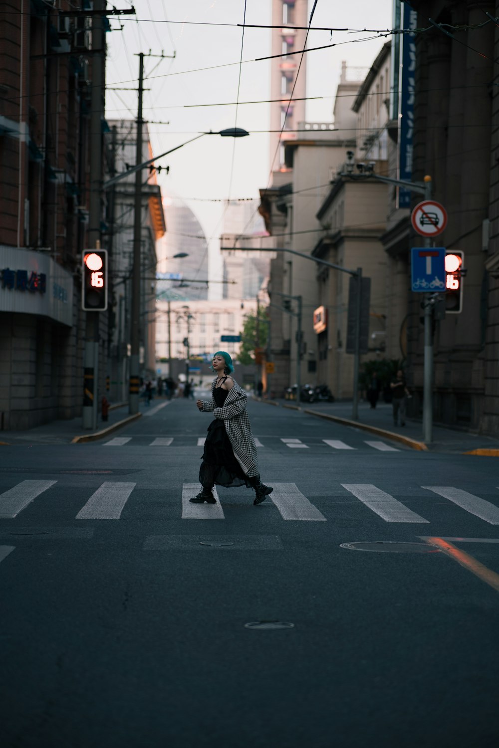 a woman walking down a street next to tall buildings