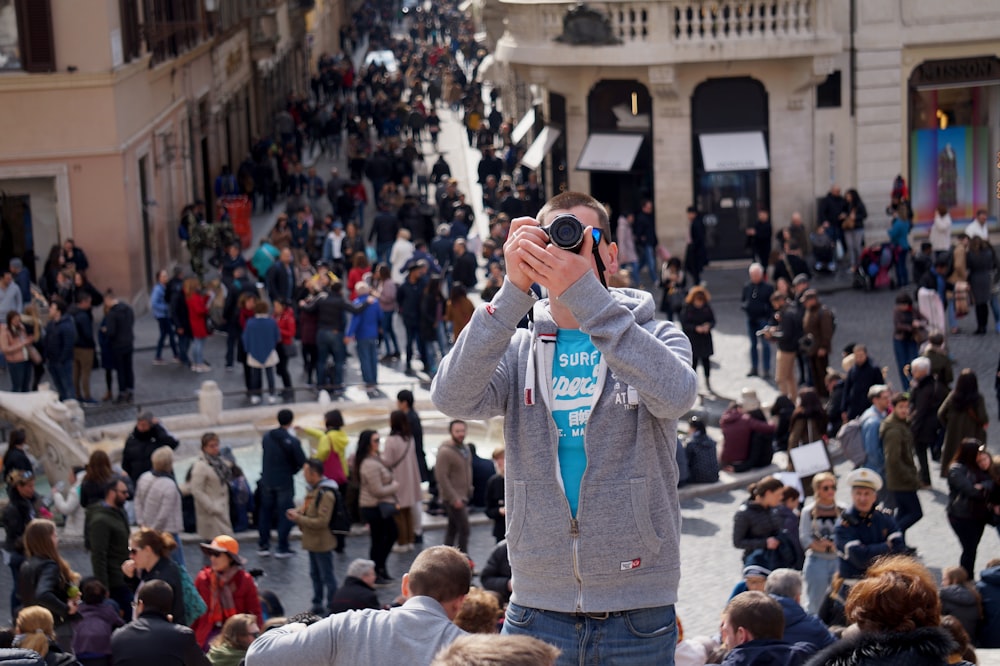 Uomo in giacca di jeans blu che scatta foto di persone durante il giorno