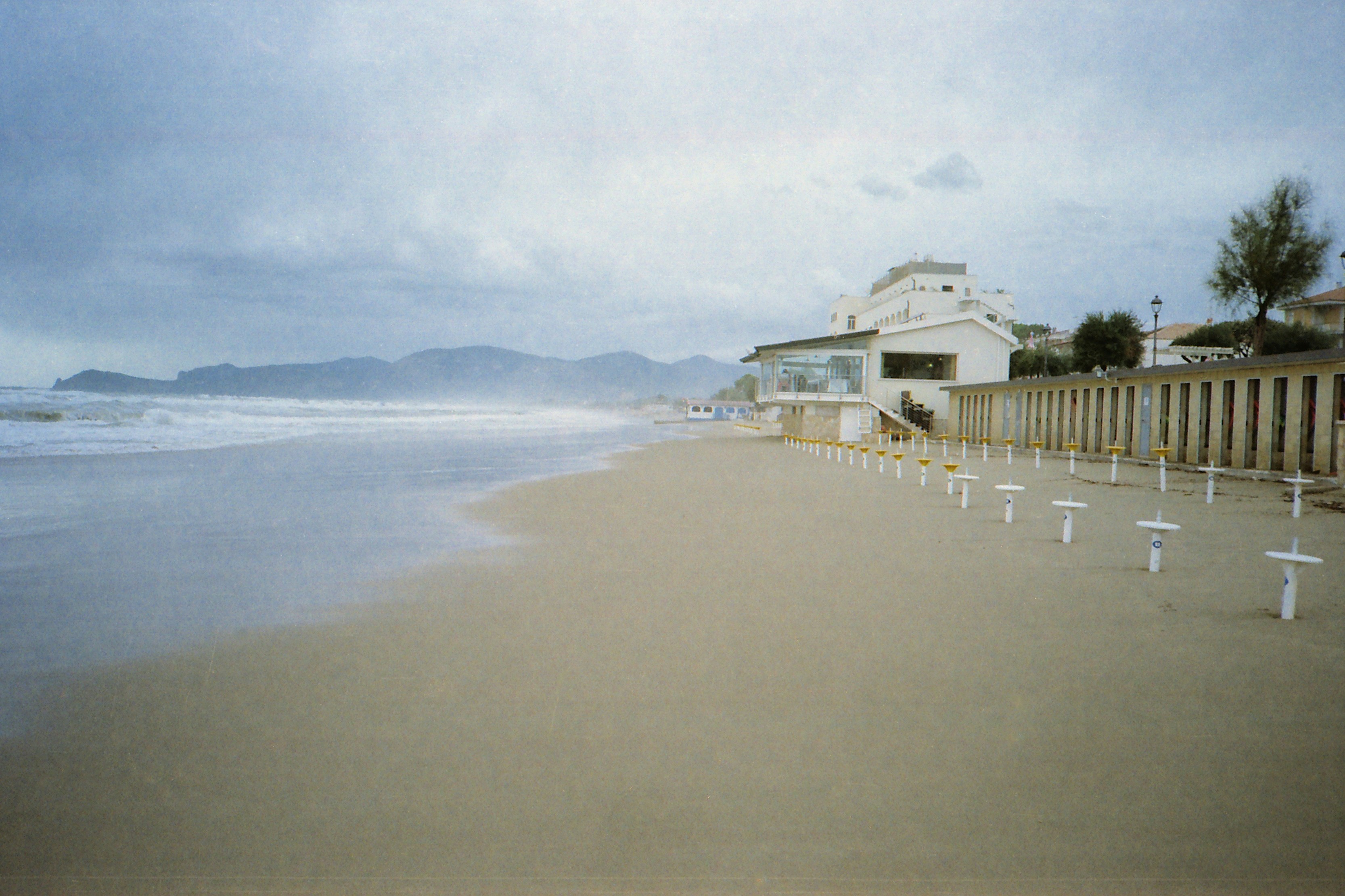 white wooden houses on beach during daytime, Hazy autumn day at the beach. Sperlonga, Lazio, Italy. Olympus XA on Kodak Color Plus film.