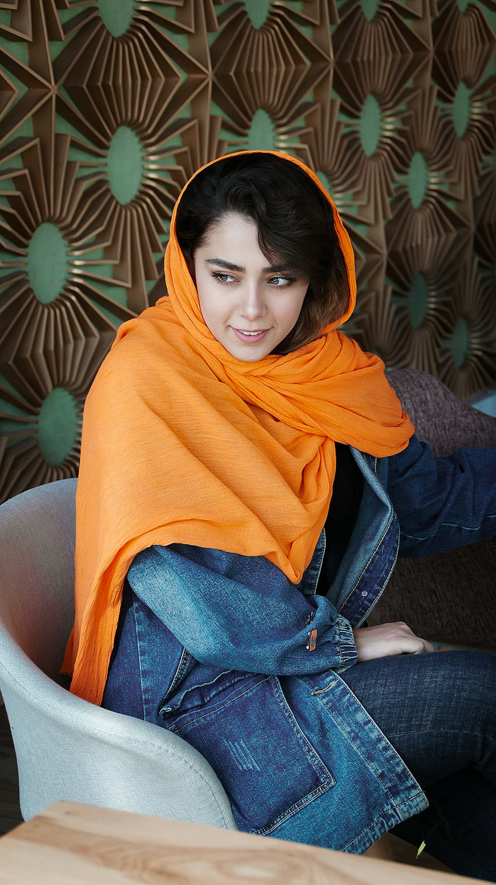 woman in yellow hijab and blue denim jacket sitting on brown sofa