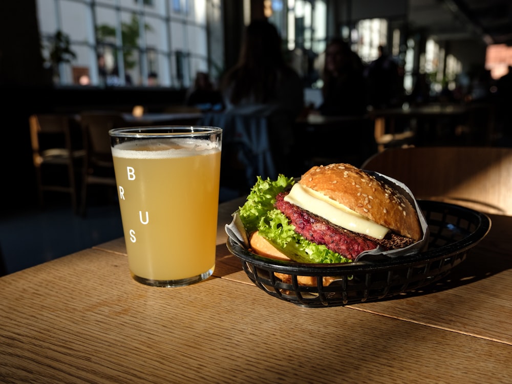 burger on black ceramic bowl beside clear drinking glass on brown wooden table