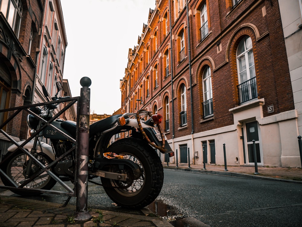 black motorcycle parked beside brown concrete building during daytime