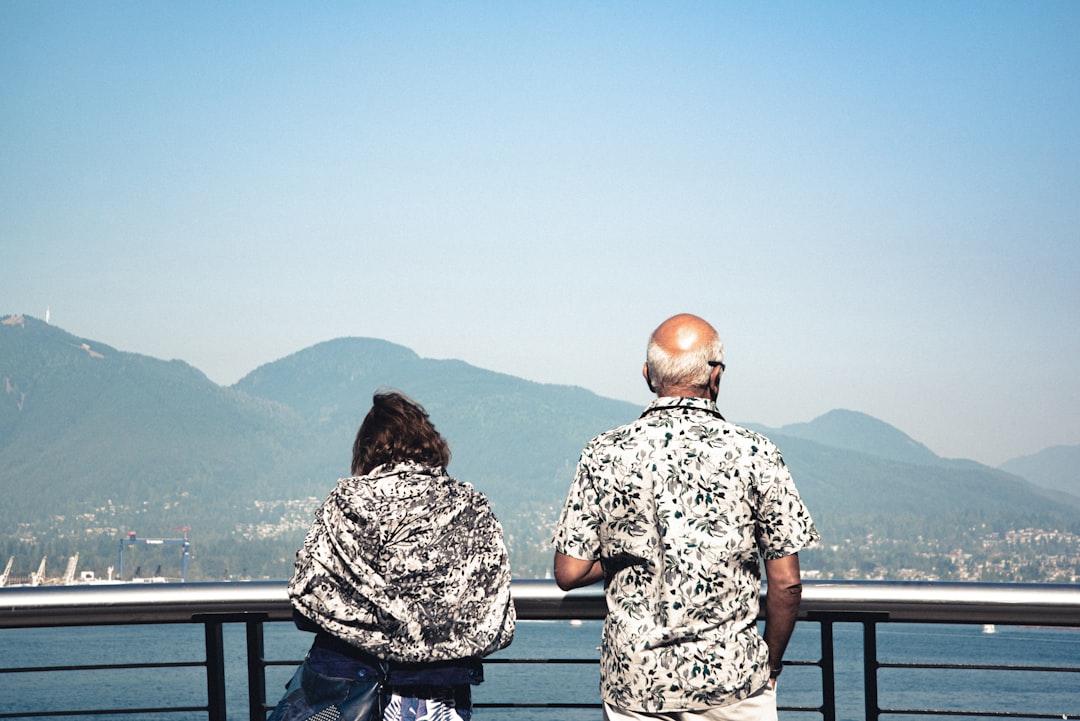 2 women sitting on bench looking at the mountains during daytime