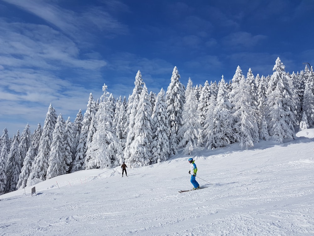 2 person in green jacket and blue pants riding ski blades on snow covered ground during