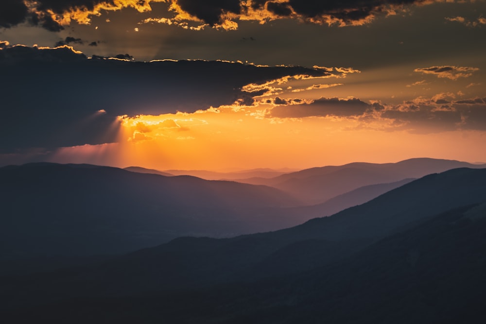 silhouette of mountains under cloudy sky during daytime