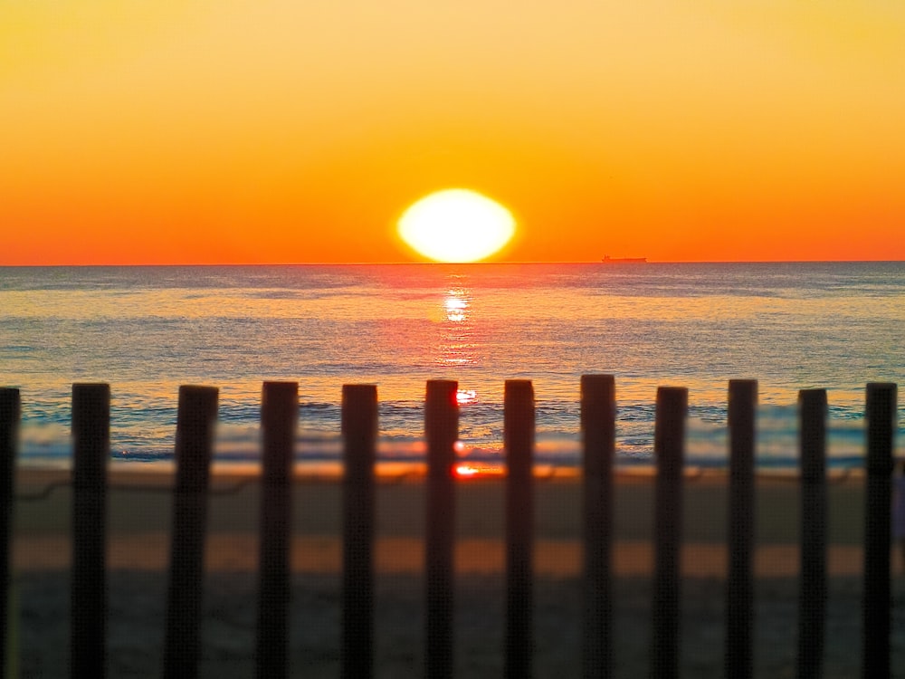 recinzione di legno marrone sulla spiaggia durante il tramonto