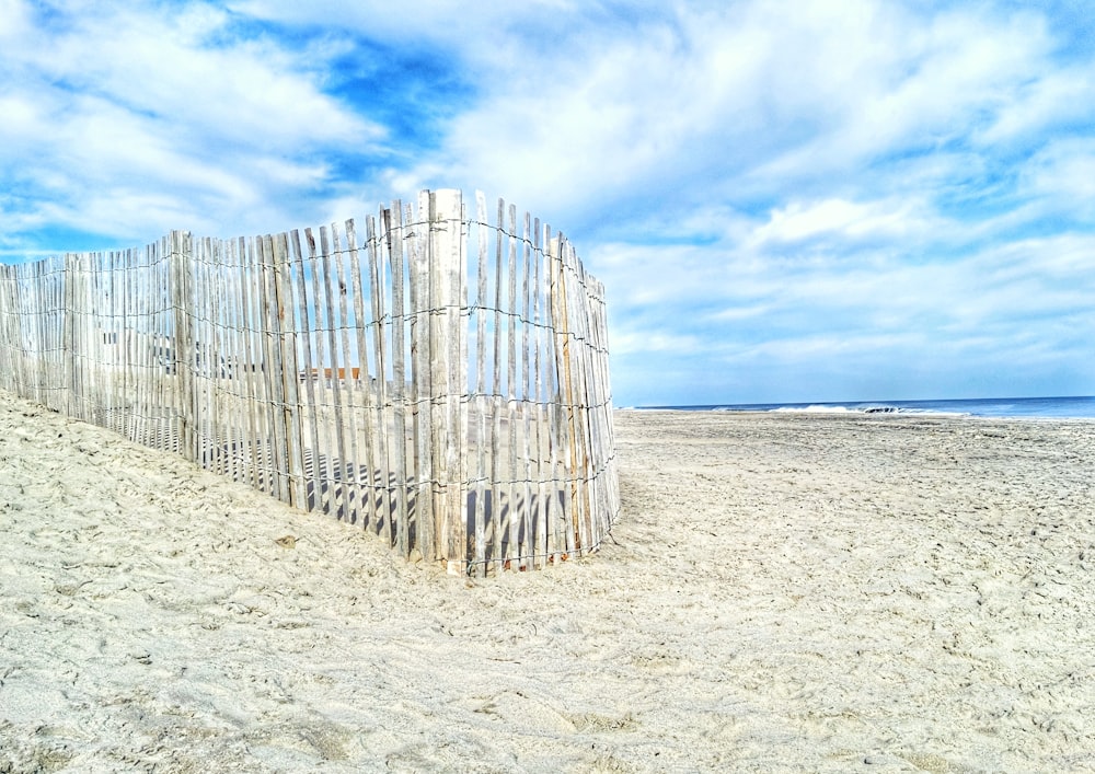 brown wooden fence on white sand during daytime
